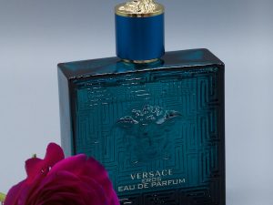 red rose beside green and gold perfume bottle